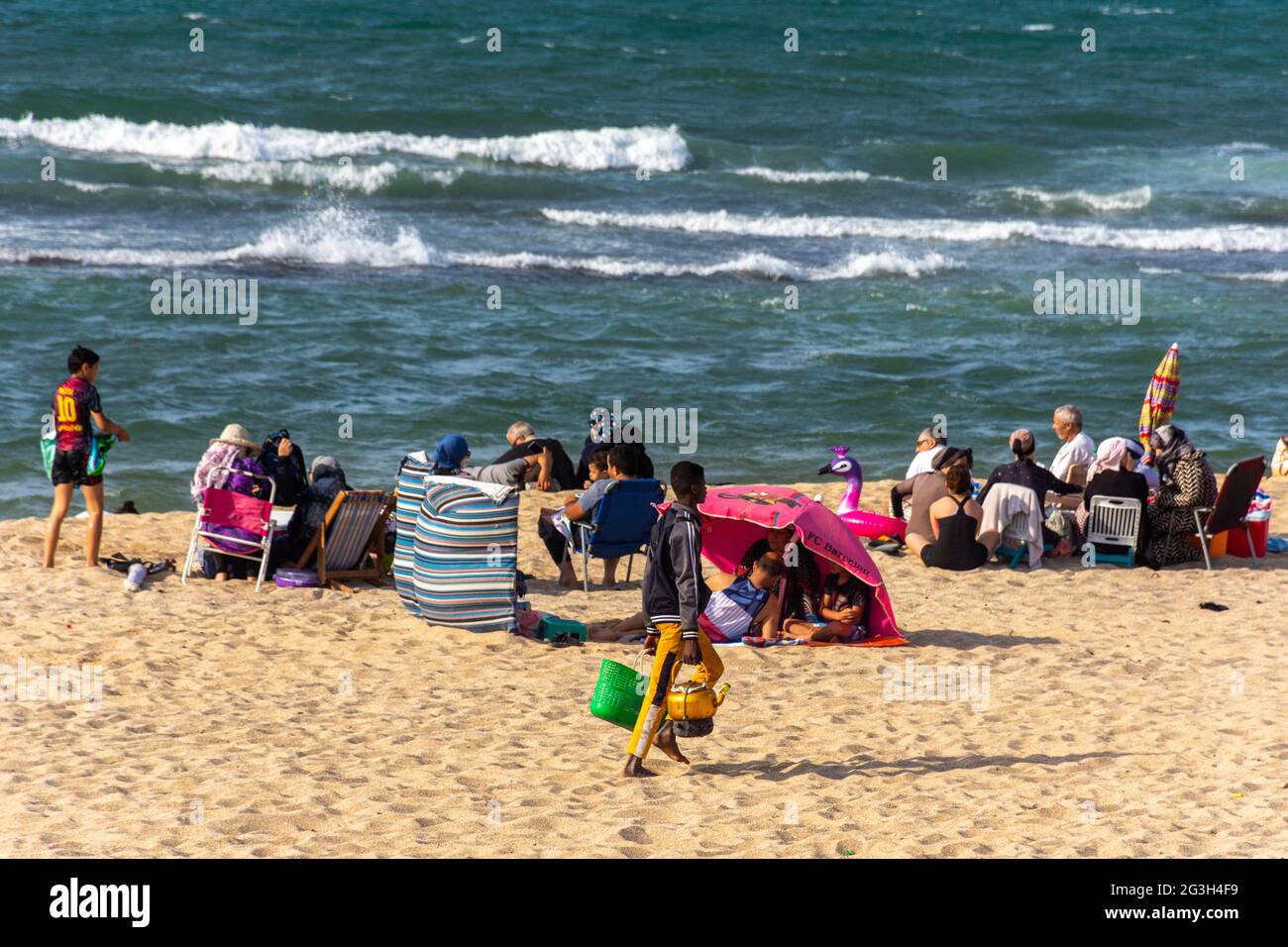 Gruppe junger Leute am Strand, kleiner Junge, der Tee verkauft, Sommerferien. Stockfoto