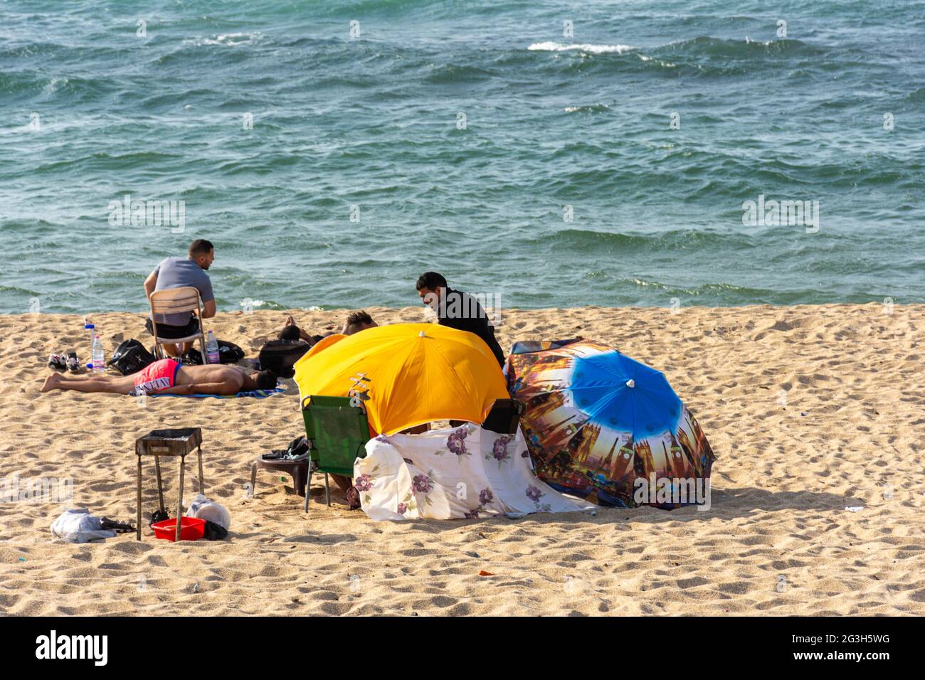 Gruppe junger Leute am Strand, Sommerurlaub, Sonnenschirme Stockfoto