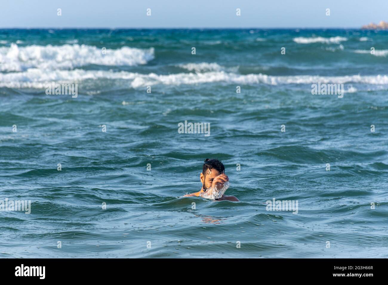 Ein junger Mann ertrinkt im Meer und winkt mit der Hand um Hilfe. Stockfoto