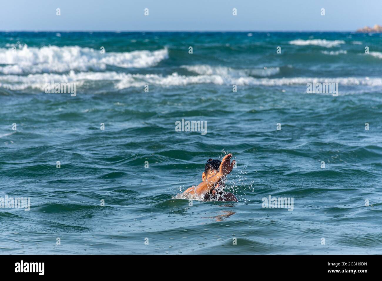 Ein junger Mann ertrinkt im Meer und winkt mit der Hand um Hilfe. Stockfoto