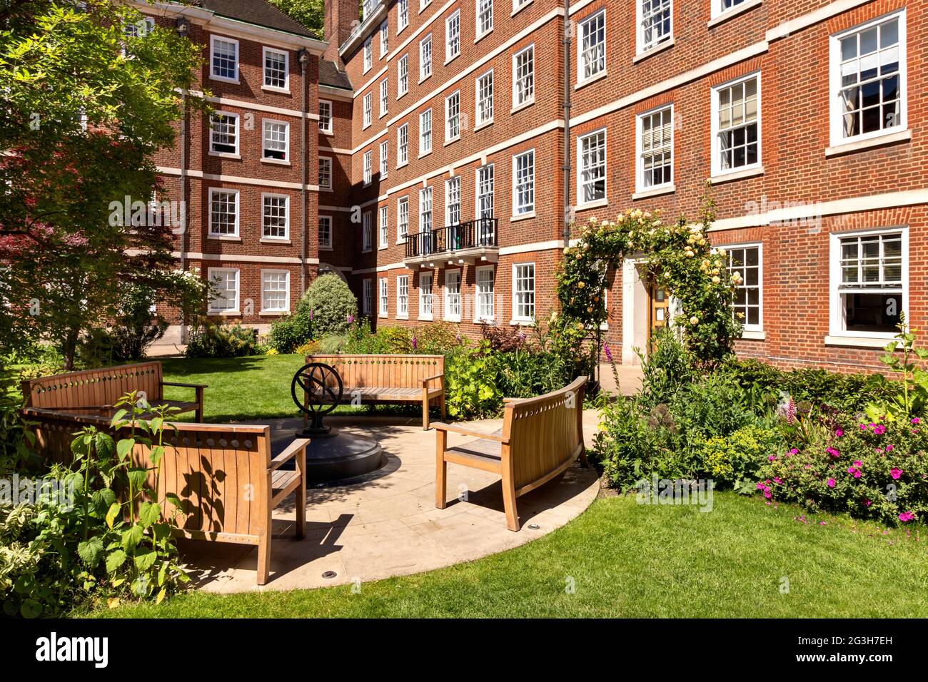 LONDON ENGLAND MITTLERE TEMPELGÄRTEN MIT HOLZBÄNKEN UND EINEM TORBOGEN AUS GELBEN ROSEN IM FRÜHSOMMER Stockfoto