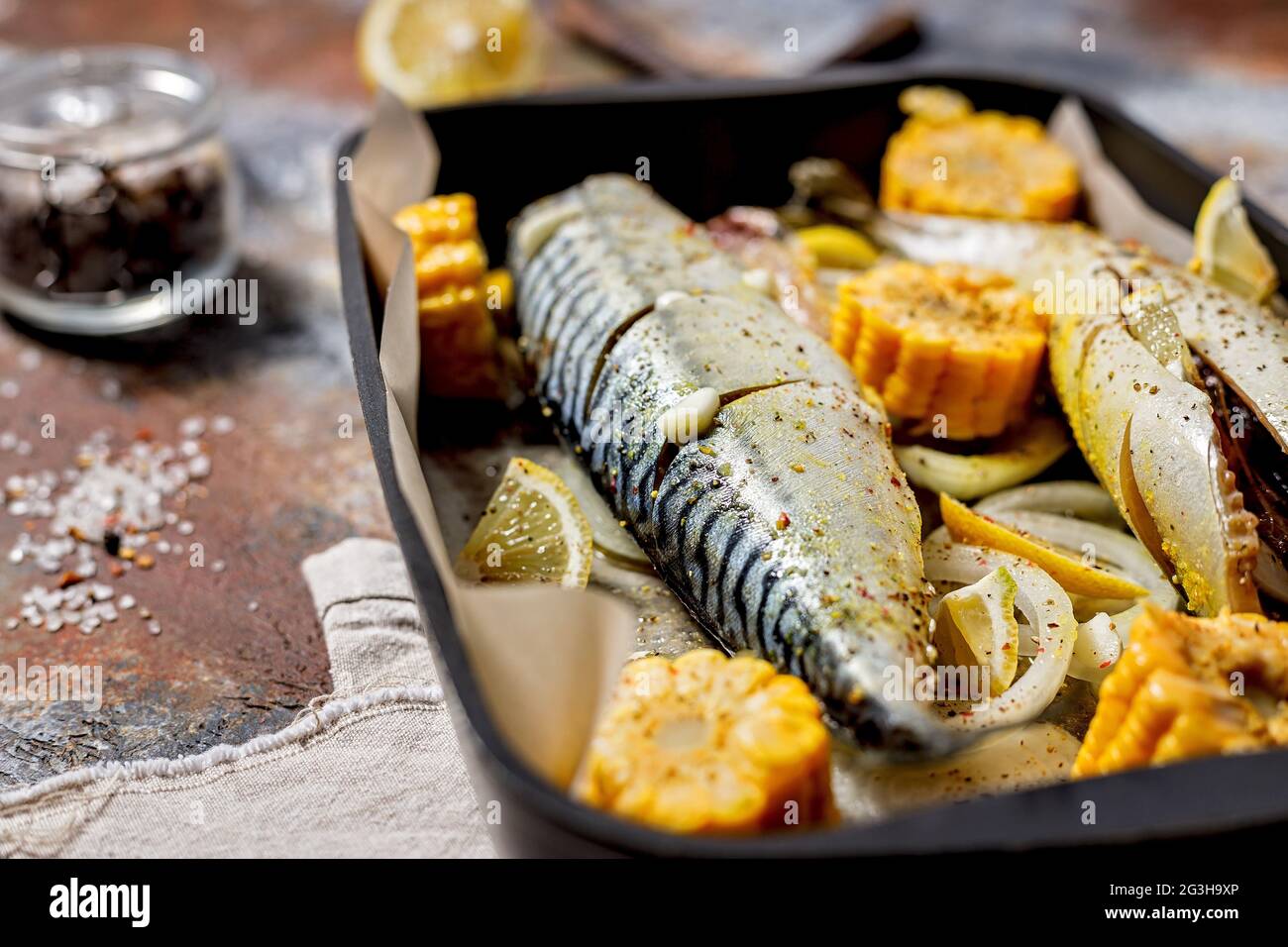 Marinierte Makrele mit weichem Brennpunkt und Gemüse. Salzwasserfisch mit Gewürzen und Gemüse in einer gusseisernen Backform auf rustikalem Hintergrund. Gesund und Stockfoto
