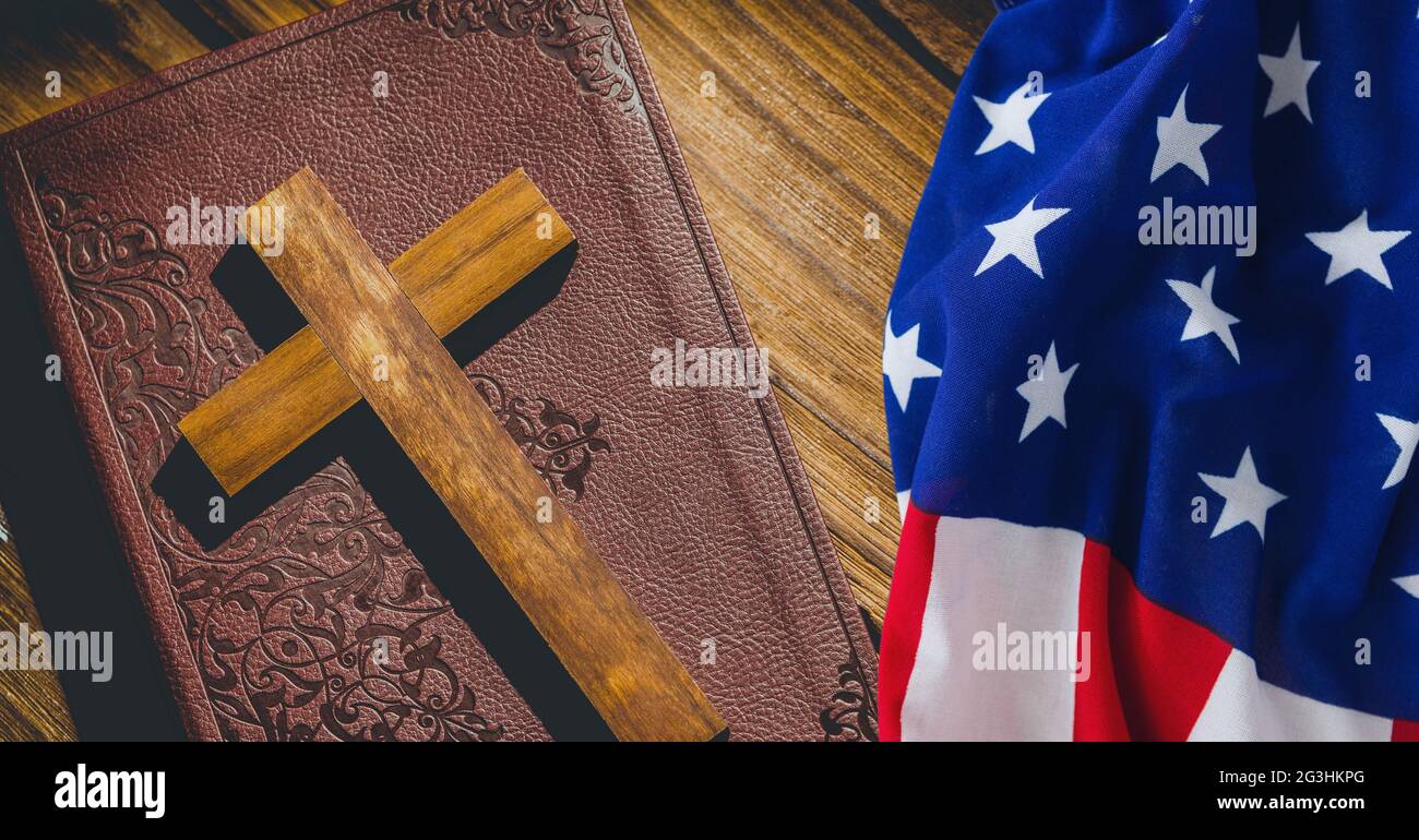 Amerikanische Flagge über Holzkreuz über bibel vor Holzhintergrund Stockfoto