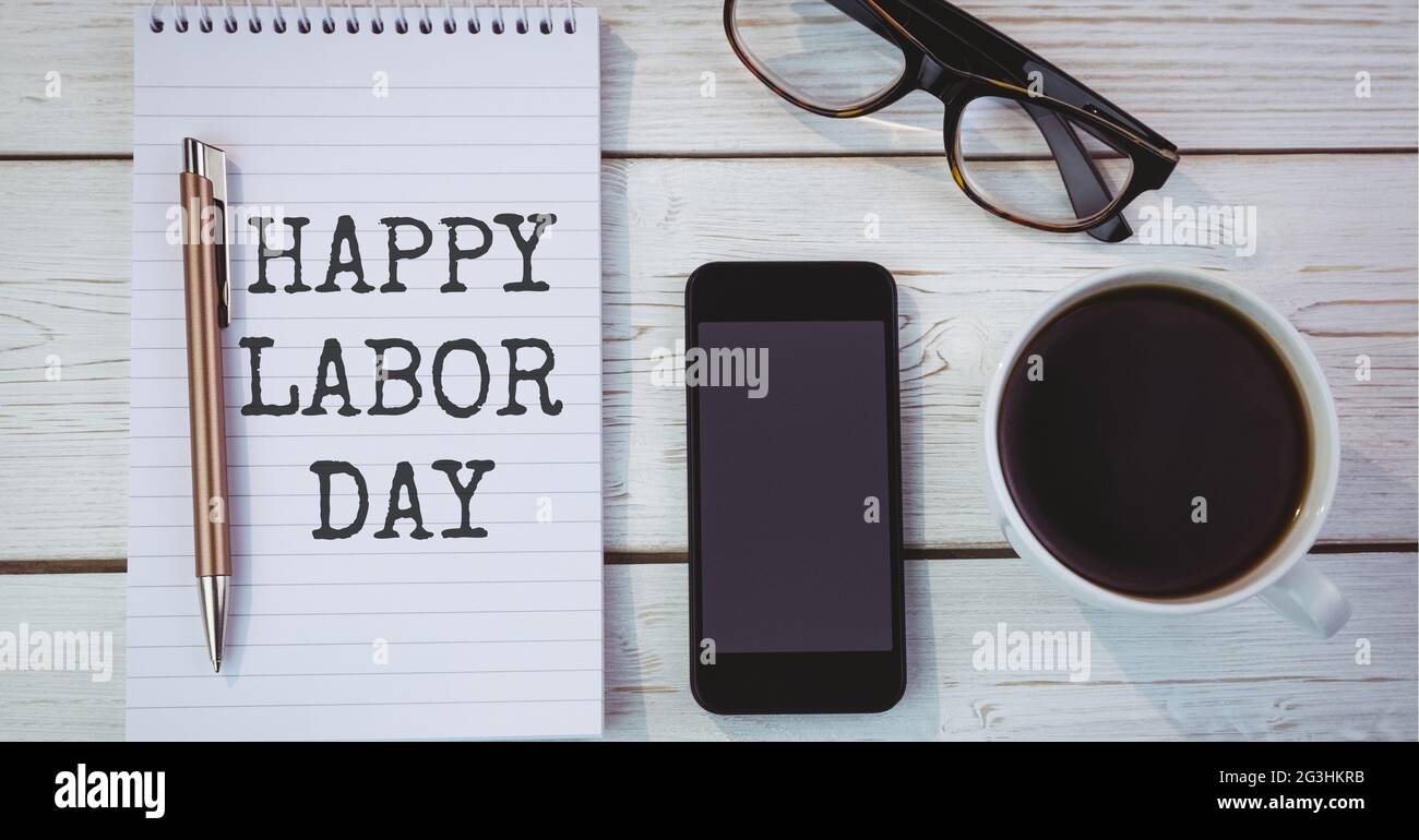 Happy Labor Day Text über Tagebuch gegen Kaffeetasse, Brille und Smartphone auf Holzhintergrund Stockfoto