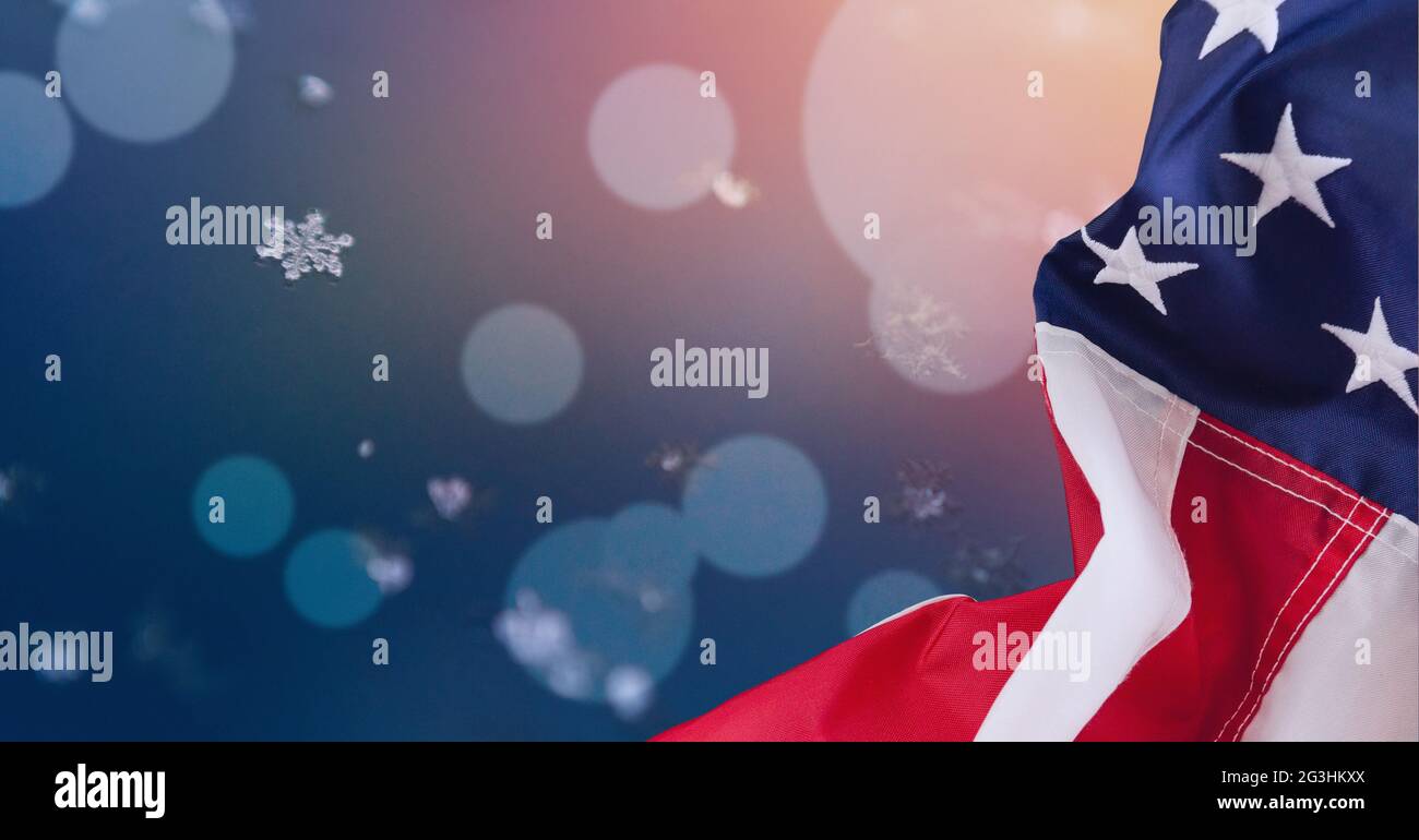 Zusammensetzung aus Schneeflocke und Bokeh weißem Licht mit amerikanischer Flagge am blauen Himmel Stockfoto
