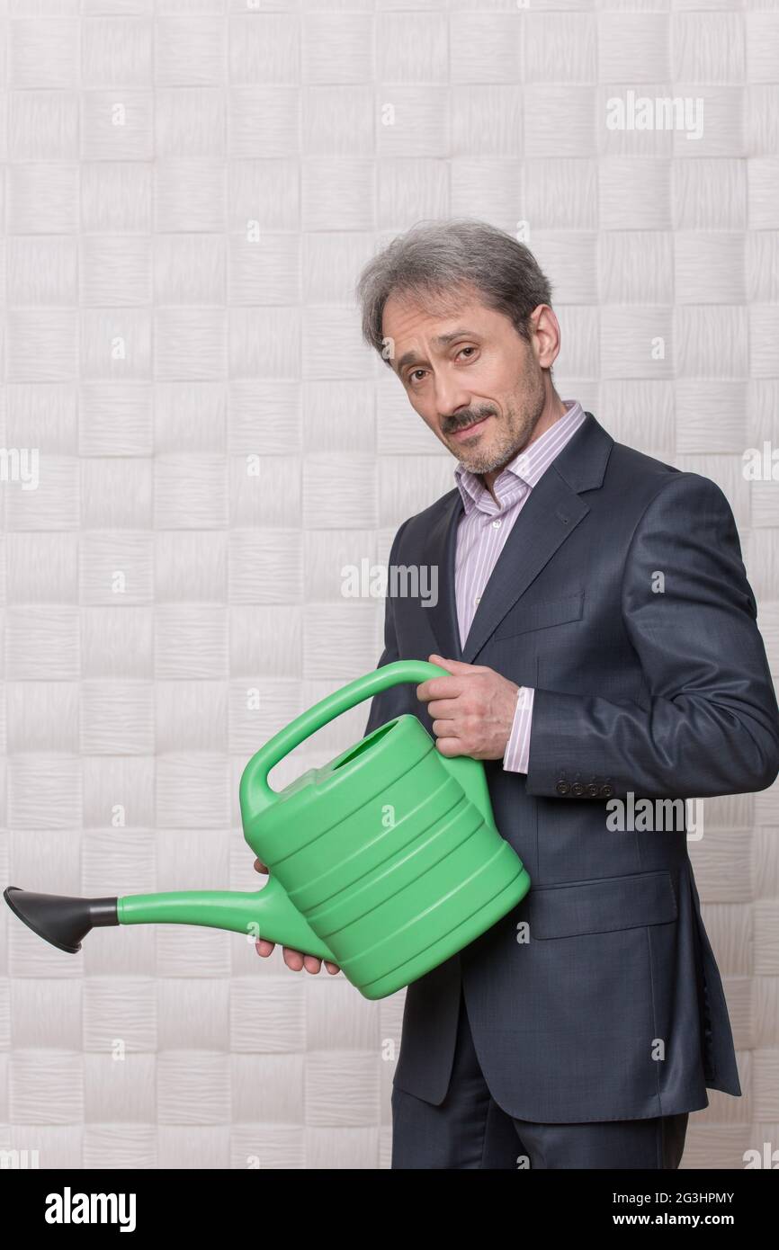 Reife Geschäftsmann mit Bewässerung Topf Stockfoto