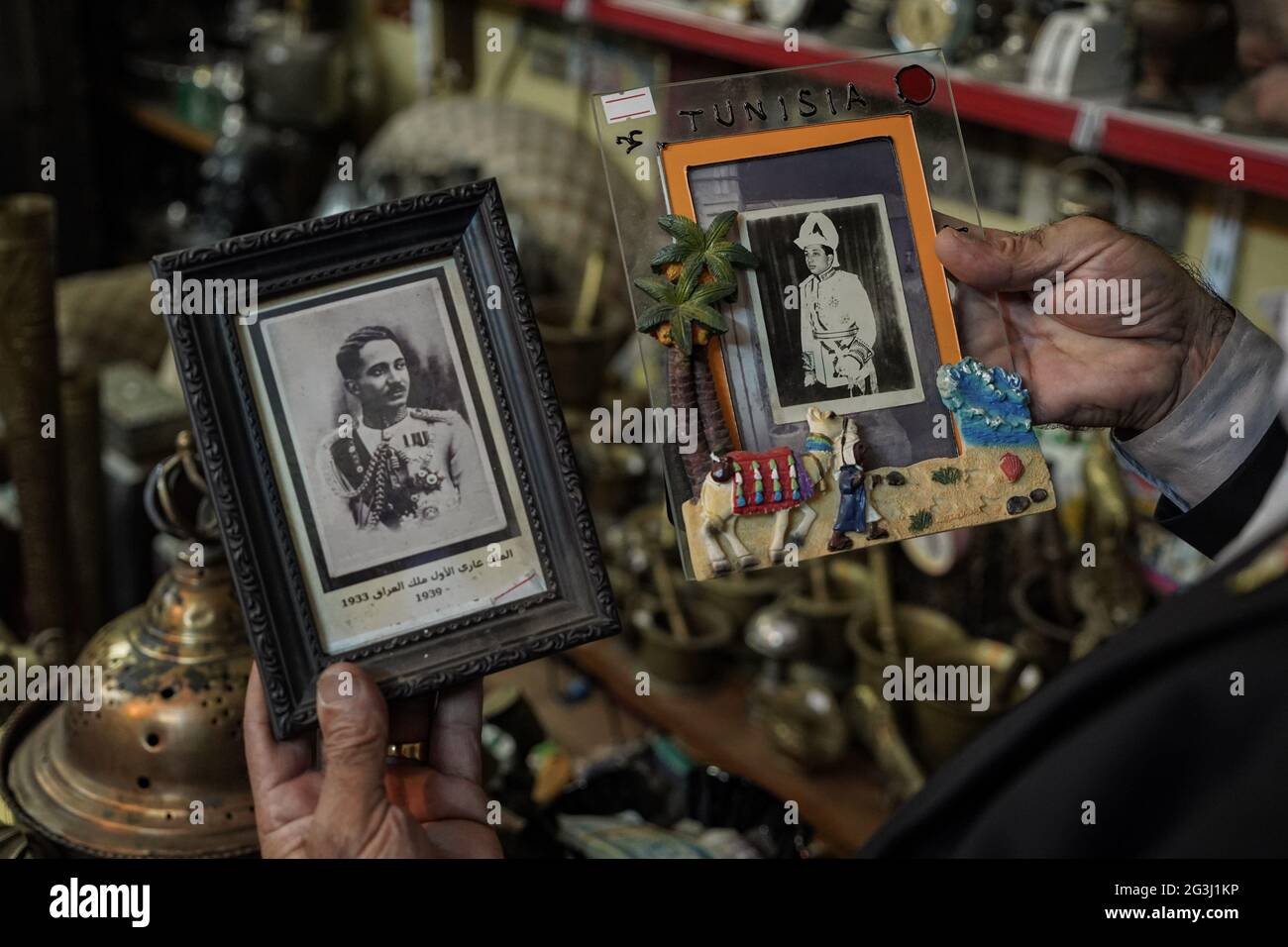 16. Juni 2021, Irak, Mosul: Der Iraker Fakhri Suleiman Al-Tai hält zwei gerahmte Bilder des letzten irakischen Monarchen, König Faisal II., als Teil einer Sammlung antiker Stücke, die er nach seiner Rückkehr nach Mosuls Altstadt nach seiner Befreiung von der Terrororganisation des sogenannten Islamischen Staates (IS) gesammelt hatte. Al-Tai beschloss, sein Haus in ein temporäres Museum umzuwandeln, in dem er mehr als 5,000 Stücke zeigt, die das Erbe und die Geschichte von Mosul widerspiegeln, das zwischen 2014 und 2017 unter der Herrschaft des Islamischen Staates schwer beschädigt wurde. Al-Tai gab fast 33,000 US-Dollar aus, um seiner Leidenschaft zu folgen Stockfoto