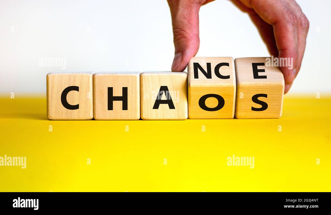 Symbol für Zufall oder Chaos. Geschäftsmann dreht Holzwürfel und ändert das Wort „Chaos“ in