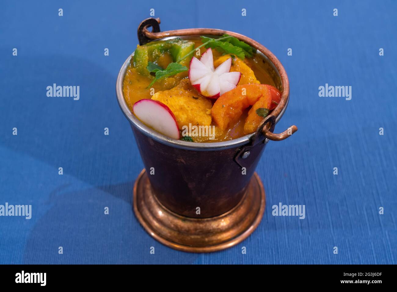 Draufsicht auf ein köstliches Huhn balti mit indischen Gewürzen auf blauem Hintergrund in einer Metallschale. Stockfoto