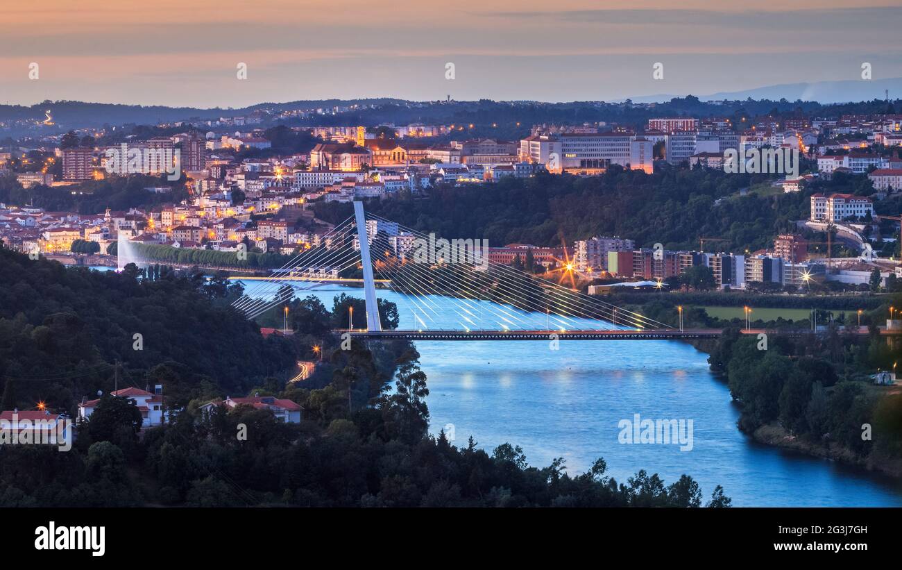 Panoramablick auf Coimbra in der Abenddämmerung, in Portugal, mit dem Fluss Mondego und der Rainha Santa Isabel Brücke im Vordergrund. Stockfoto