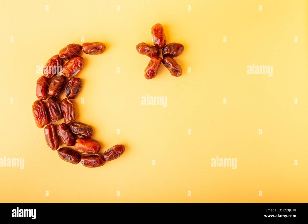 Ramadan-Kareem mit getrockneten Datteln, die in Form eines Halbmondes auf gelbem Hintergrund angeordnet sind. Iftar Food-Konzept. Platz für Text. Stockfoto