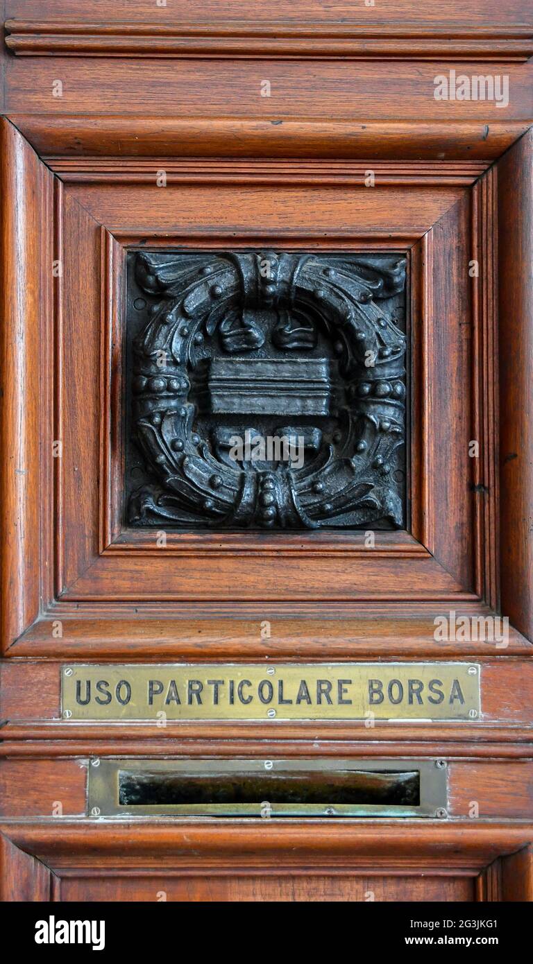Nahaufnahme der Holztür des Börsenpalastes im Zentrum von Genua, mit einem Briefkasten und einer Bronzedekoration im Liberty-Stil, Italien Stockfoto