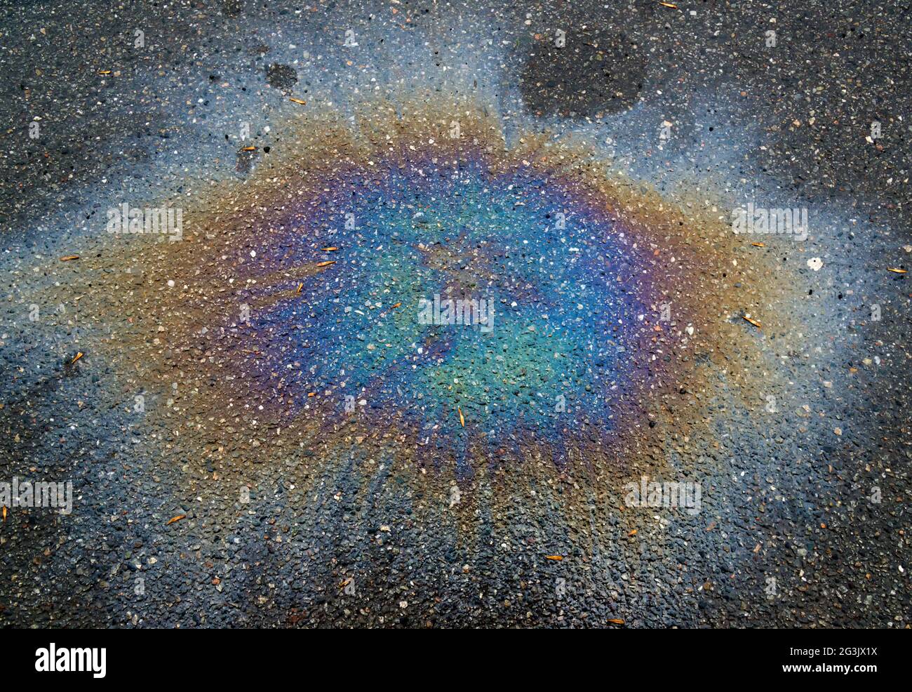Bunte Gasfleck auf nassem Asphalt. Dies ist die Art von Flecken, die durch ein Leck unter einem Auto oder Lkw verursacht wird. Stockfoto