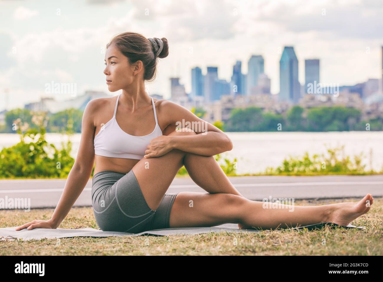 Yoga-Stretch-Übung fit Asiatische Frau Stretching unteren Rücken für die Gesundheit der Wirbelsäule auf Stadt Outdoor-Fitness-Klasse im Park. Sitzende Wirbelsäulenverdrehung Stockfoto