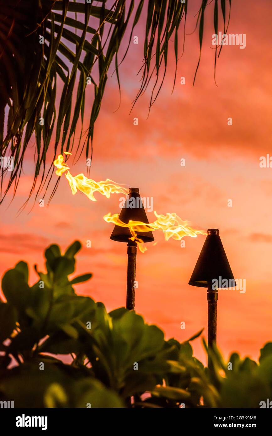 Hawaii Luau Party Maui Feuer Tiki Fackeln mit Flammen gegen Sonnenuntergang Himmel Wolken in der Nacht brennen. Hawaiianische Kultur Reise Hintergrund. Stockfoto