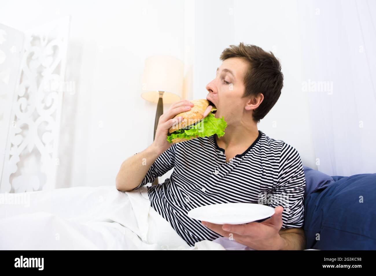 Ein Mann, der im Bett isst Stockfoto