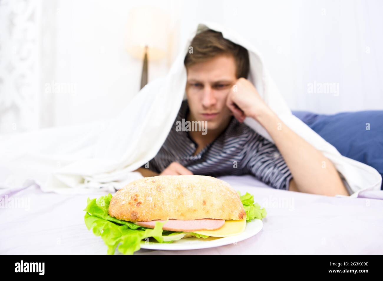 Ein Mann, der im Bett isst Stockfoto