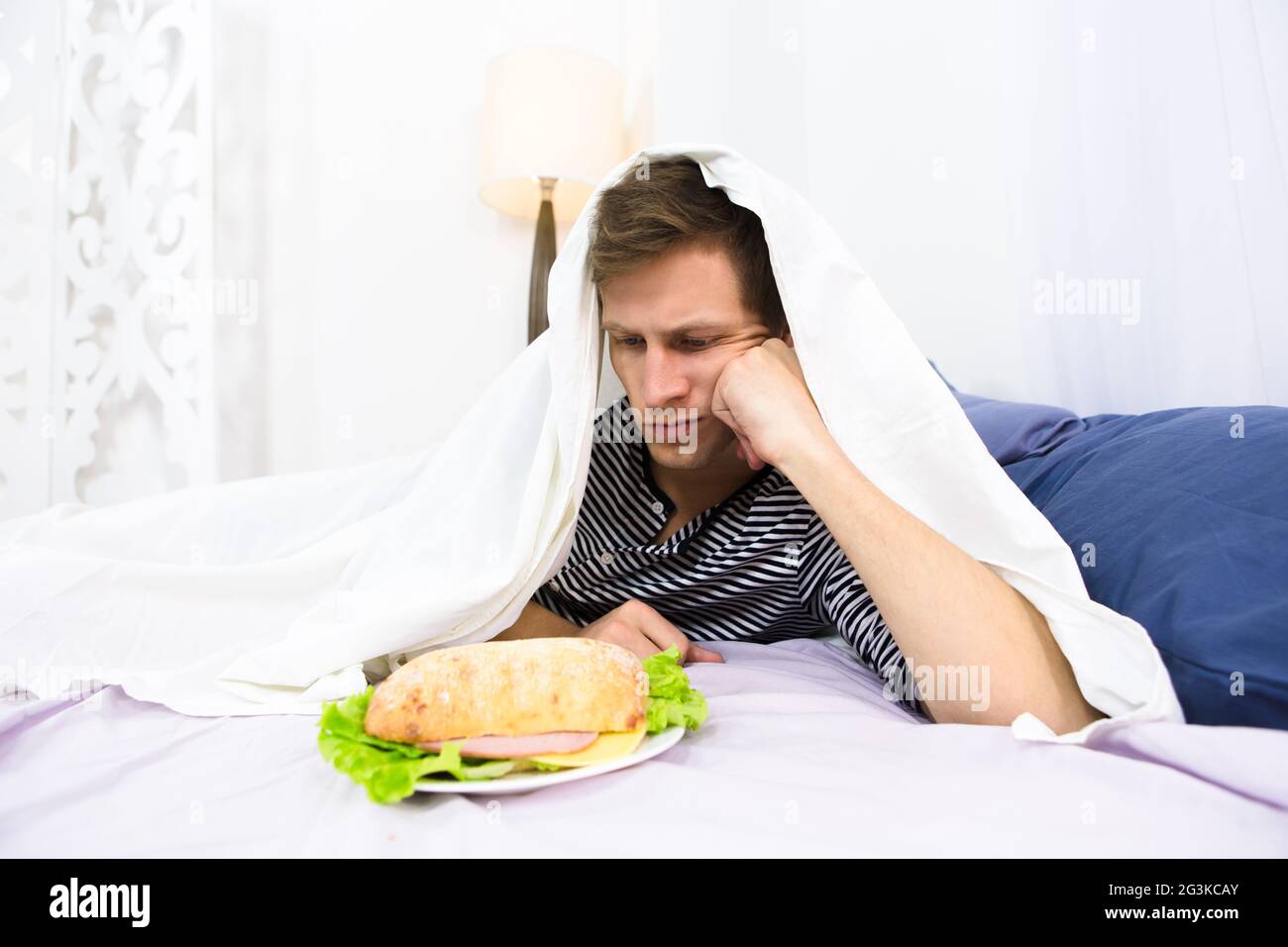 Ein Mann, der im Bett isst Stockfoto