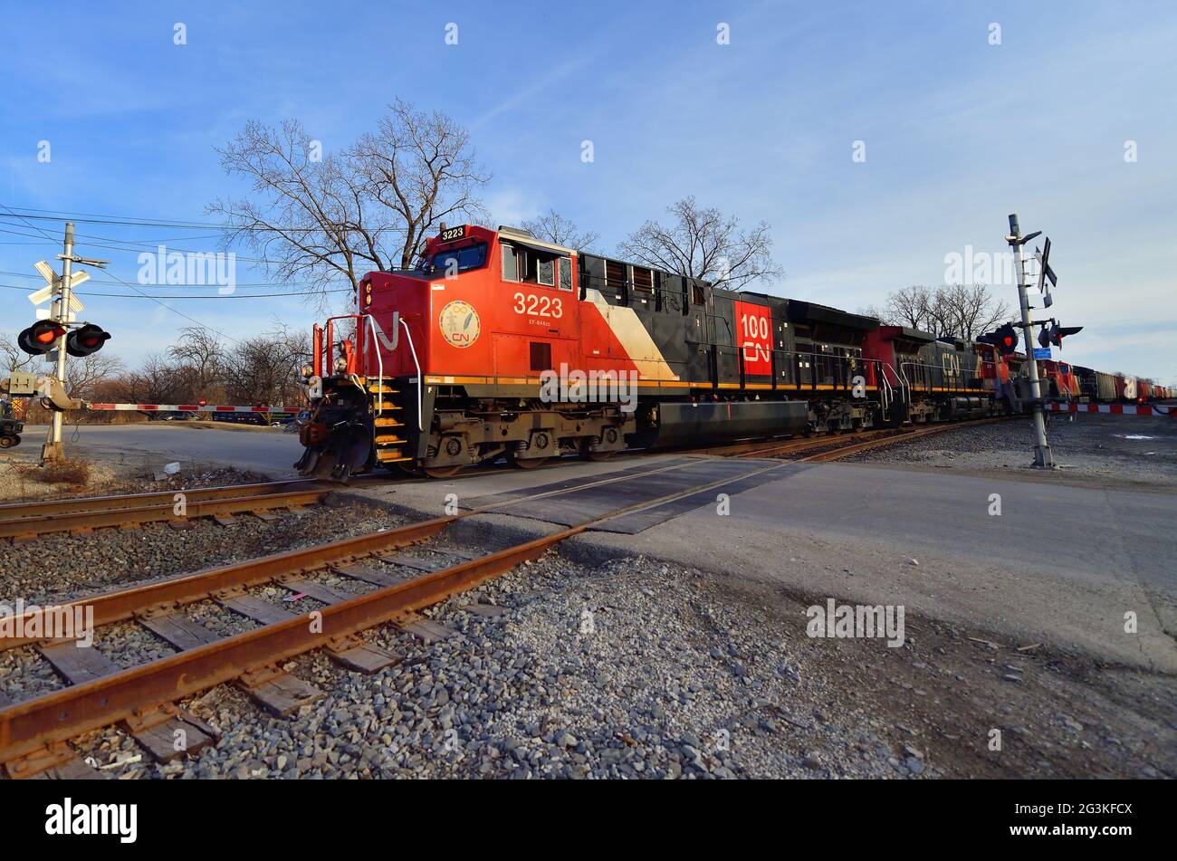 Bartlett, Illinois, USA. Vier Lokomotiven der Canadian National Railway führen einen manifesten Güterzug nach Norden durch eine von cro geschützte Bahnüberfahrt Stockfoto