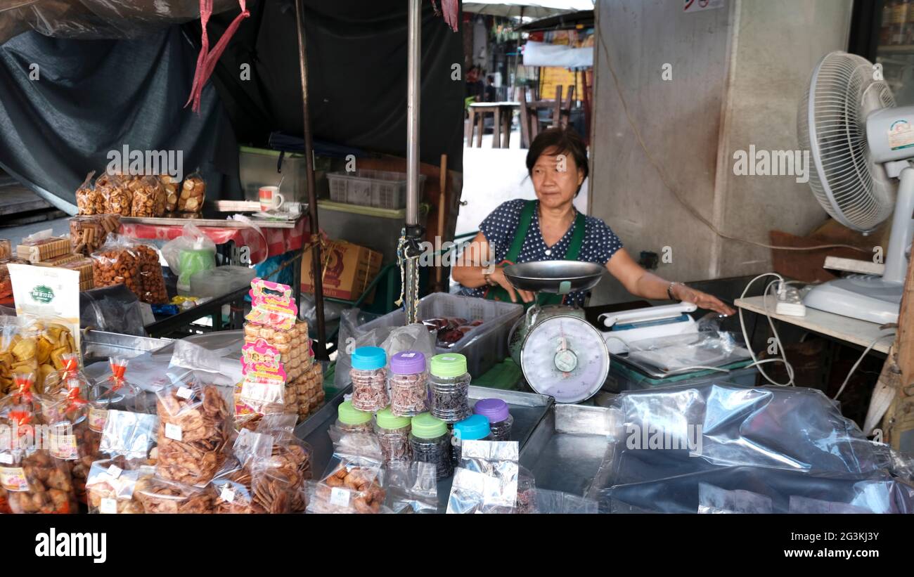 Dame mittleren Alters Verkauf von Cookies und Süßigkeiten und Süßigkeiten auf Bürgersteig bei warmem Wetter Bangkok Thailand Stockfoto