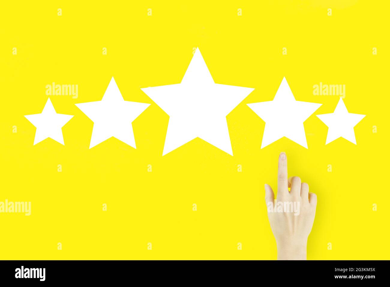 Bewertungsauswertung und Klassifizierungskonzept erhöheHandfinger der jungen Frau zeigt mit Hologramm fünf Sterne auf gelbem Hintergrund Stockfoto