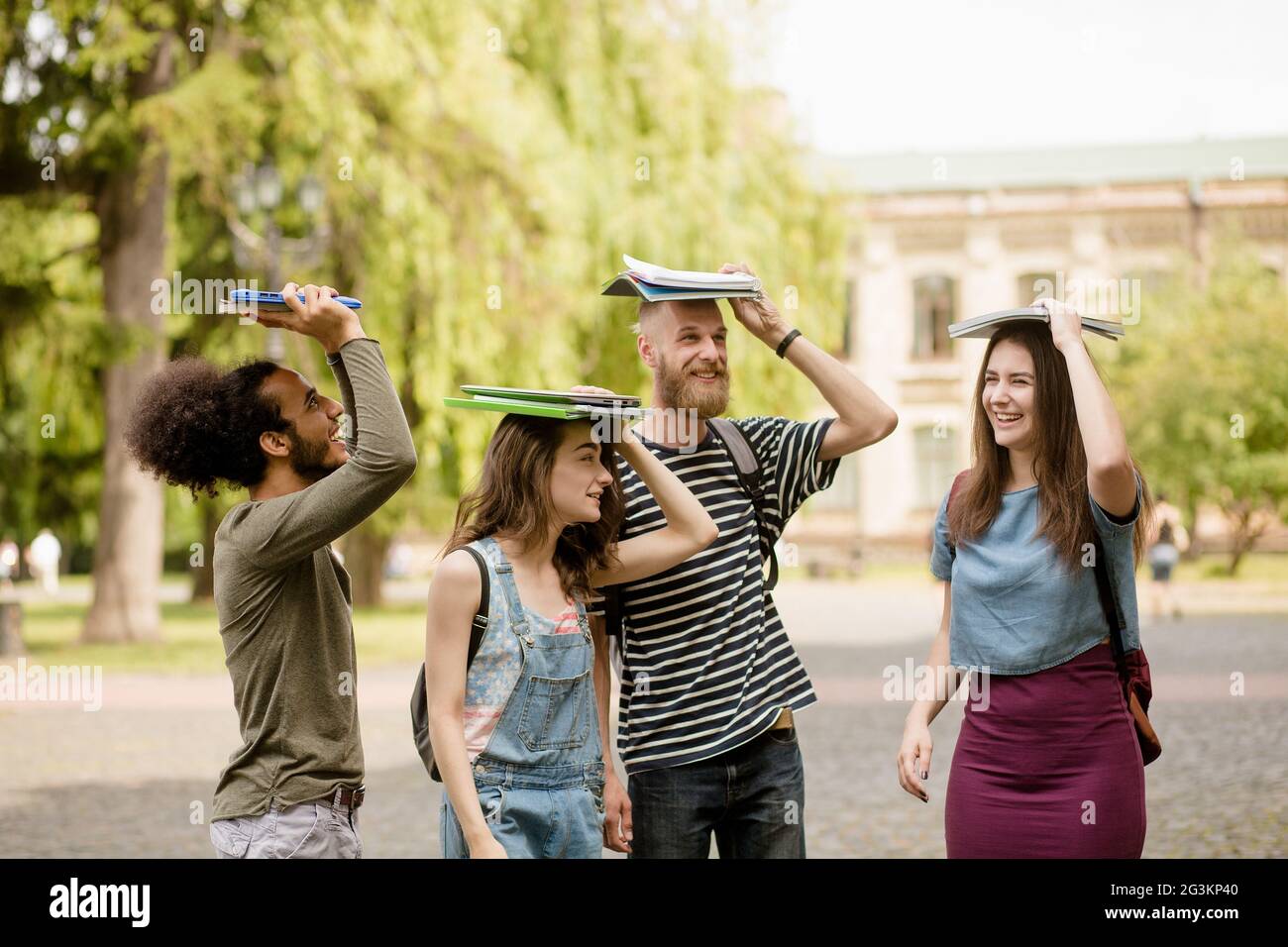 Junge College-Studenten zu Fuß mit Bücher auf ihren Köpfen. Stockfoto