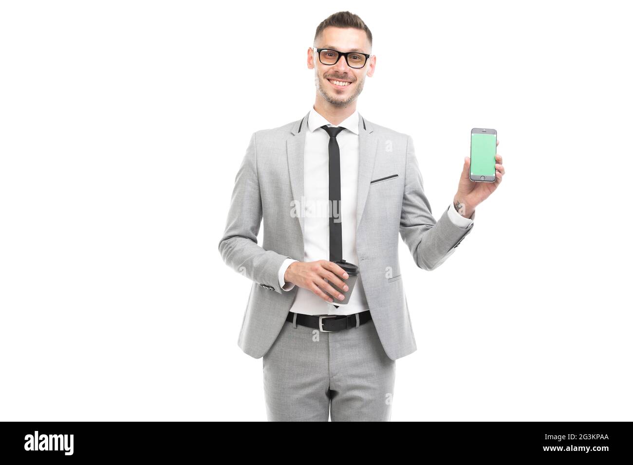 Horizontales mittleres Porträt eines hübschen jungen kaukasischen Geschäftsmannes mit grauem Anzug und Brille, die Kaffeetasse und Smartphone hält Stockfoto