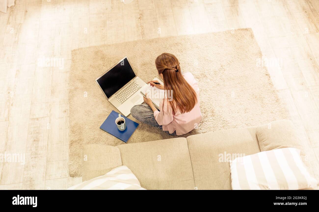 Junge Frau studieren auf dem Teppich sitzt mit dem Rücken zur Kamera. Stockfoto