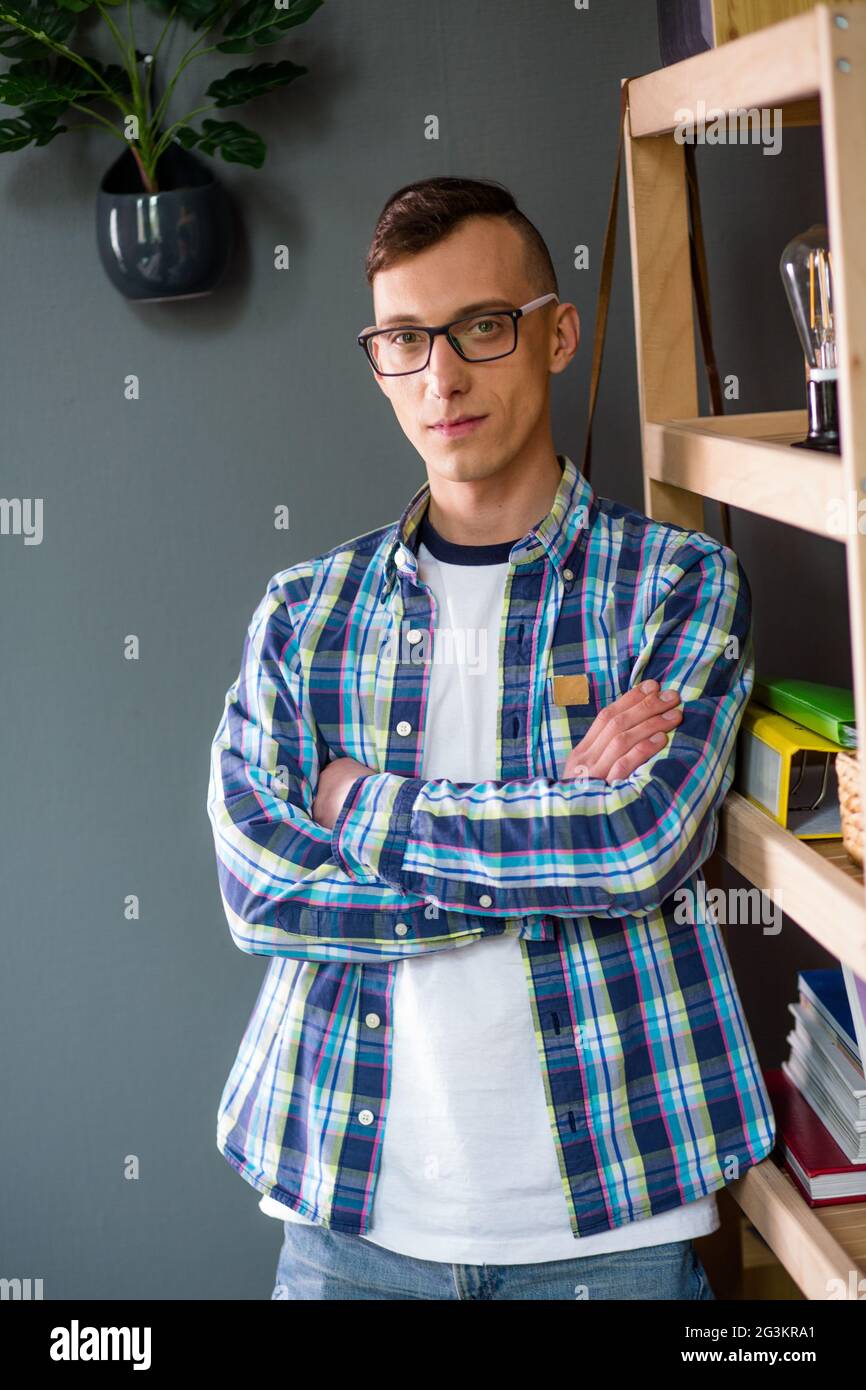 Junger Mann in legerer Kleidung und Brille, der mit gekreuzten Händen steht. Stockfoto