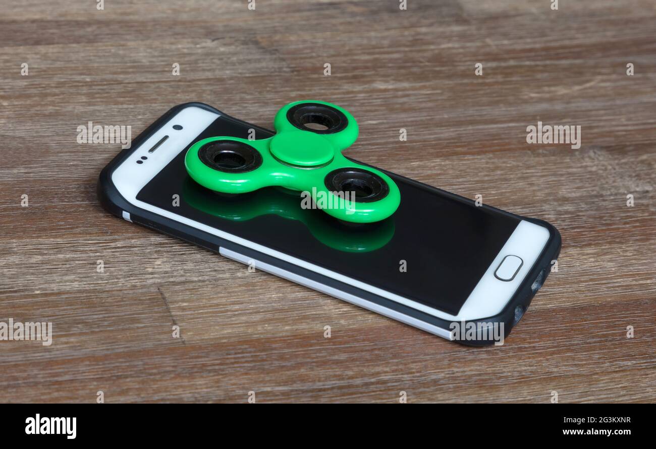 Kinderspielzeug; Smartphone mit einem Spinner auf der Oberseite Stockfoto