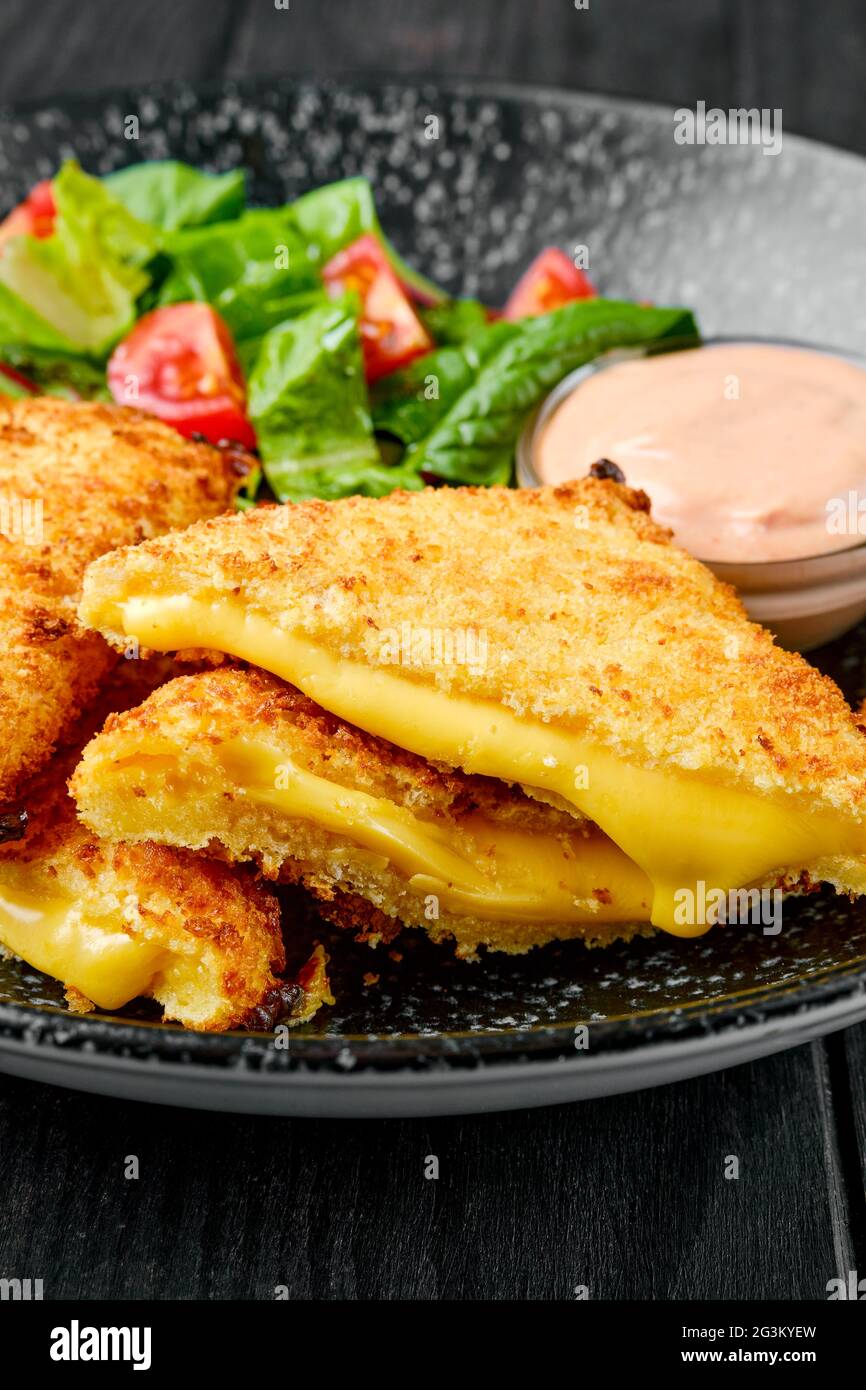 Nahaufnahme des Sandwiches mit geschmolzenem Cheddar und Salat auf einem Teller Stockfoto