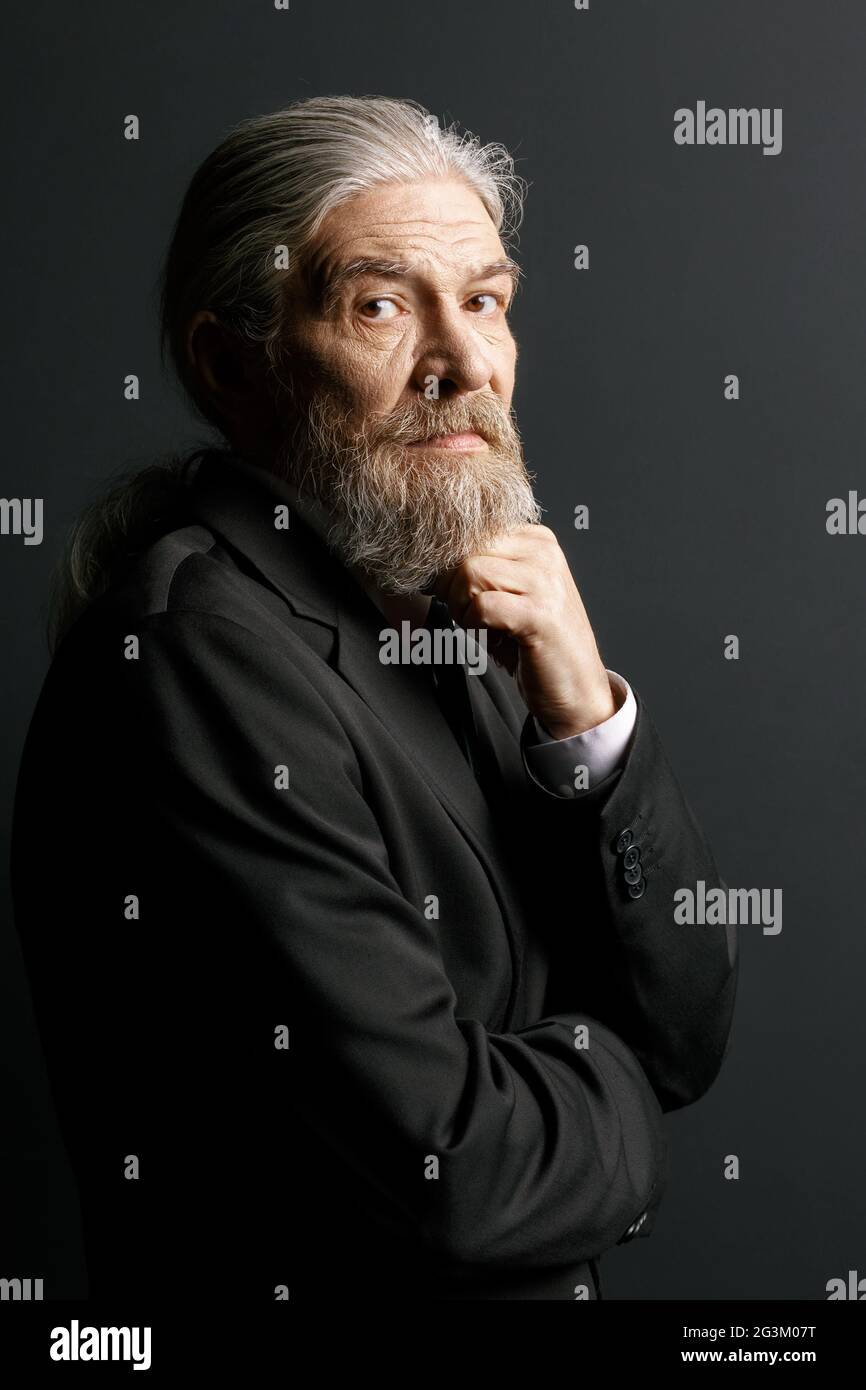 Alter Mann mit langen grauen Haaren und Bart auf schwarzem Hintergrund. Stockfoto