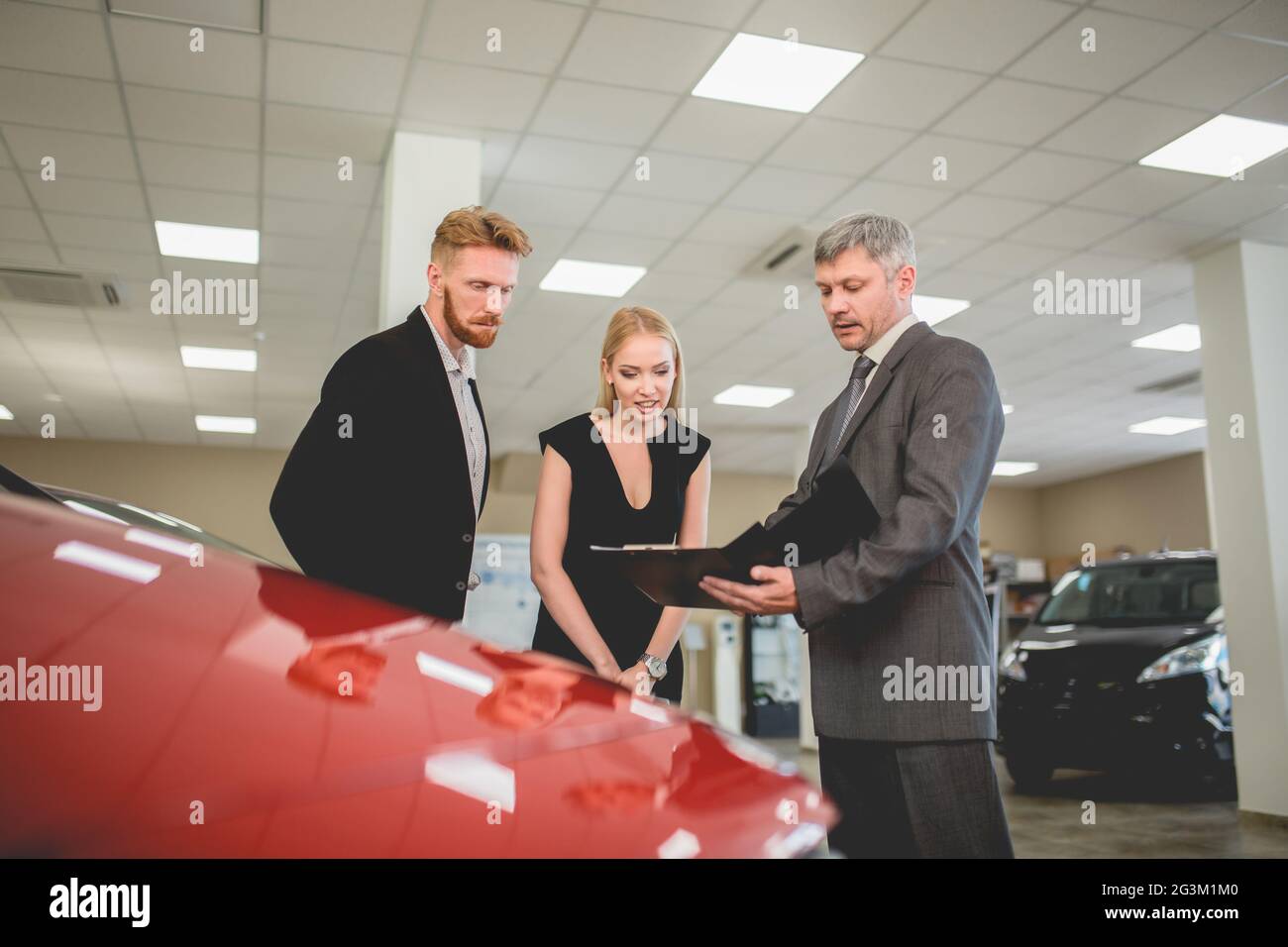 Auto-Händler-Agent zeigt Dokumente mit Auto-Spezifikationen an Käufer. Stockfoto