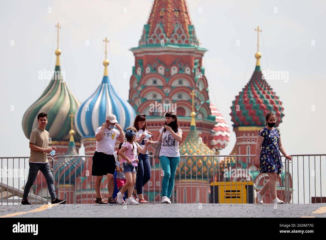 Menschen mit schützenden Gesichtsmasken gehen auf einem Roten Platz in Moskau vor dem Hintergrund der Basilius-Kathedrale. Leben in Russland und Sicherheitsmaßnahmen Stockfoto