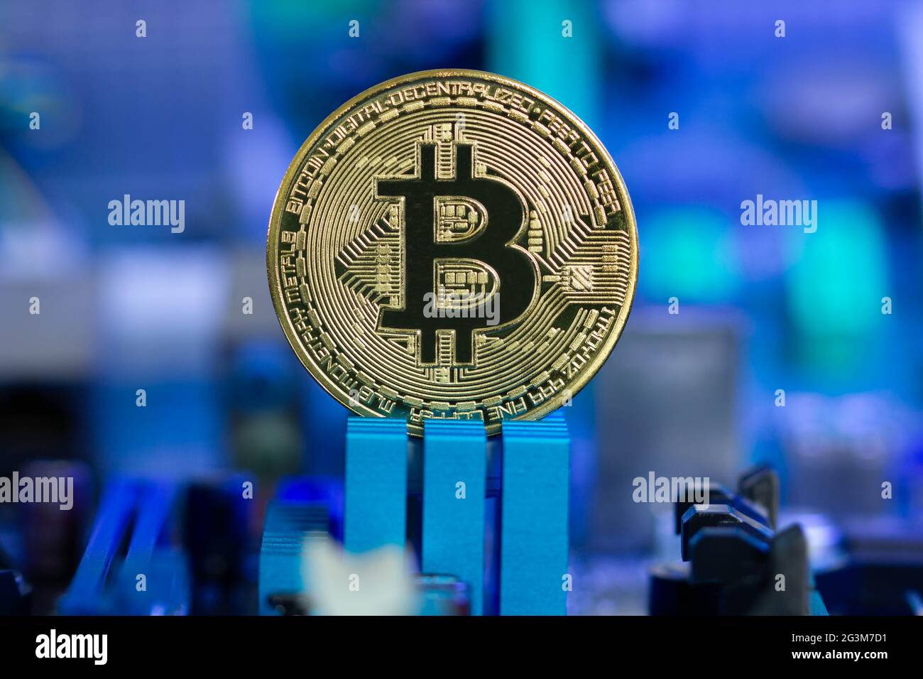 Goldene Bitcoin-Münze auf einem verschwommenen Hintergrund aus Mikrochips und Funkkomponenten in blauem Licht. Neues digitales Kryptowährungskonzept der Blockchain Stockfoto