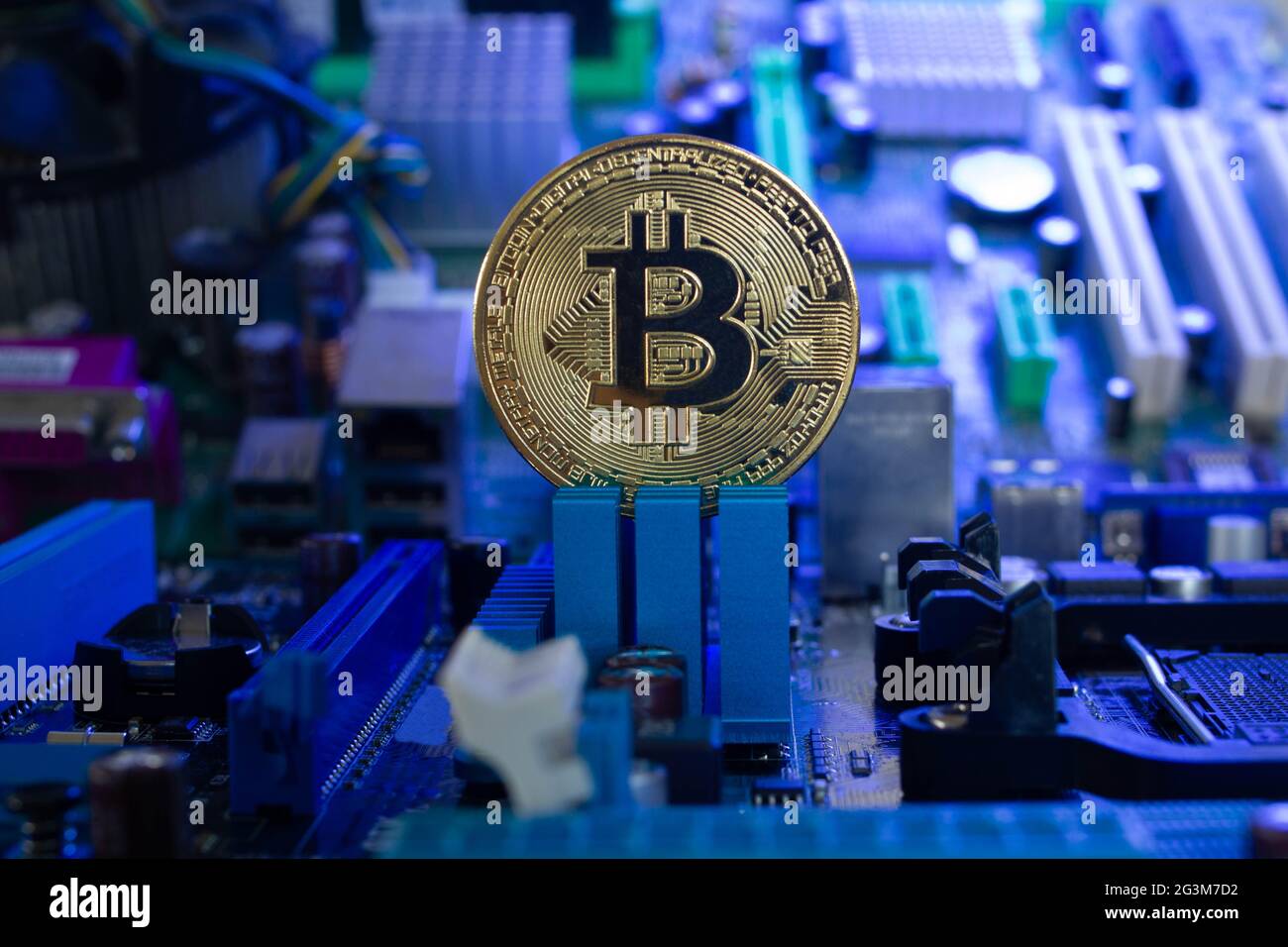 Goldene Bitcoin-Münze auf einem deutlich sichtbaren Hintergrund von Mikrochips und Funkkomponenten in blauem Licht. Neues digitales Kryptowährungskonzept Stockfoto