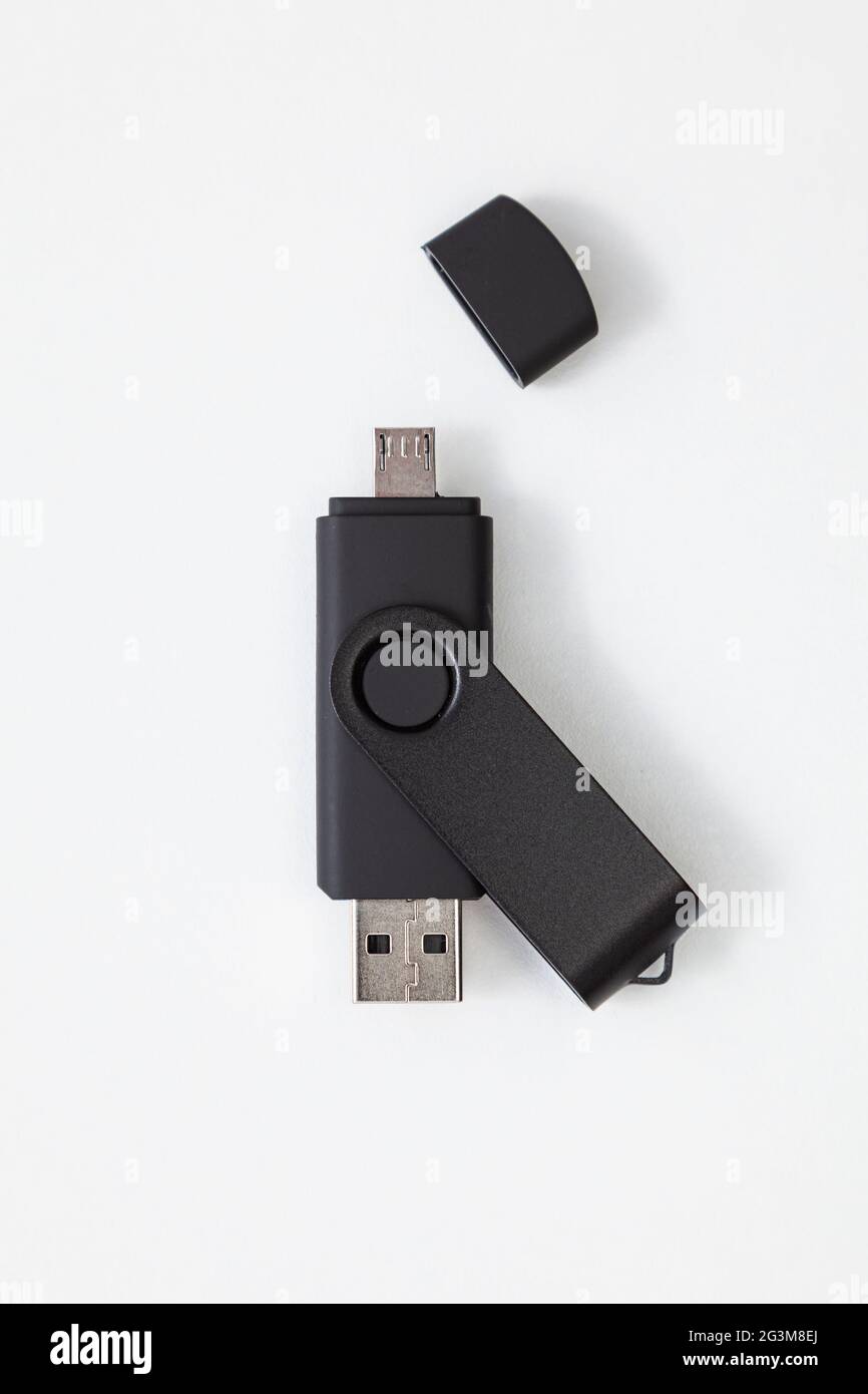 Schwarzes Pendrive mit USB- und Micro-USB-Anschlüssen auf weißem Hintergrund. Der kleine Port verfügt über einen Kaper, der entfernt wird. Stockfoto