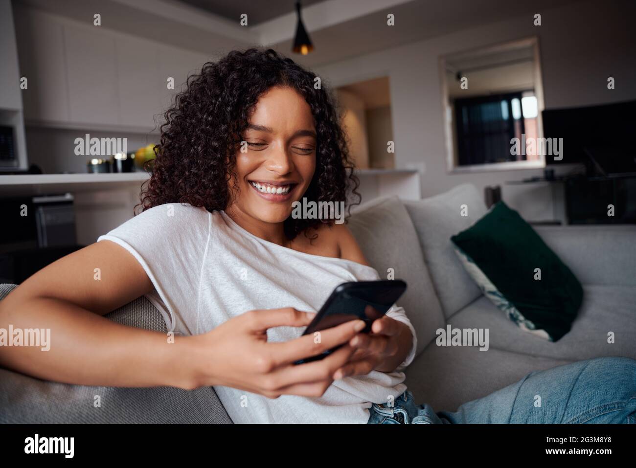 Gemischte Rasse weiblich lächeln, während SMS an Freunde auf Handy-Gerät Stockfoto