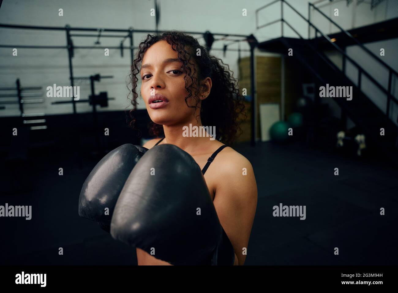 Afroamerikanische Boxerin trainiert im Fitnessstudio mit Boxhandschuhen. Mischfrauin mit Boxhandschuhen in der Luft. Hochwertige Fotos Stockfoto