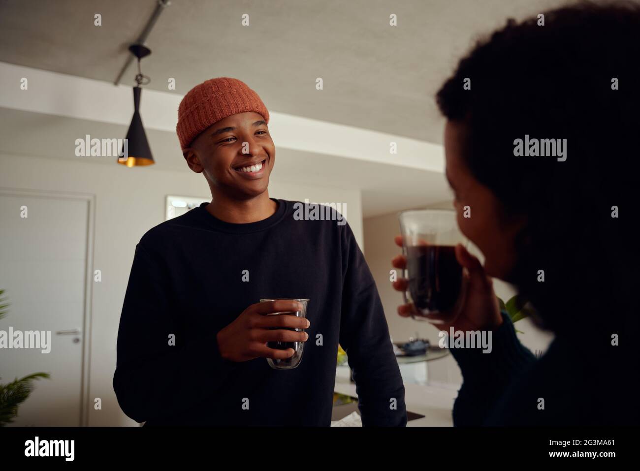 Gemischtes Rennpaar trinkt zusammen Kaffee. Junger, glücklicher afroamerikanischer Mann, der seine Partnerin anlächelt. Hochwertige Fotos Stockfoto