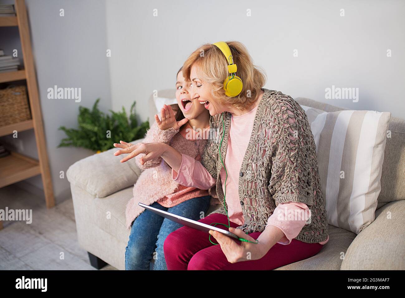 Oma und Enkelin hören zu Hause Musik Stockfoto