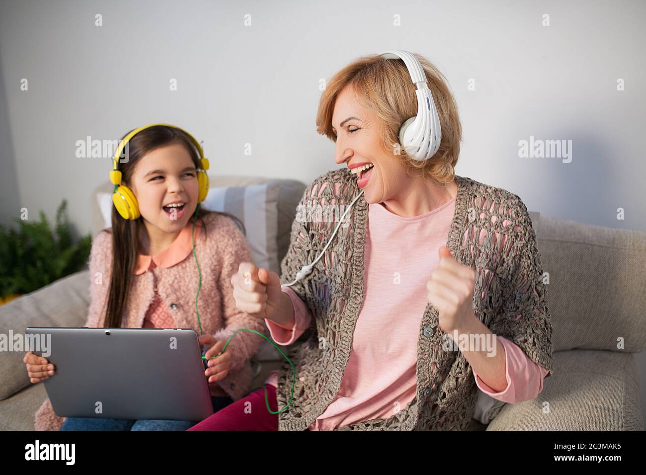 Oma und Enkelin hören zu Hause Musik Stockfoto
