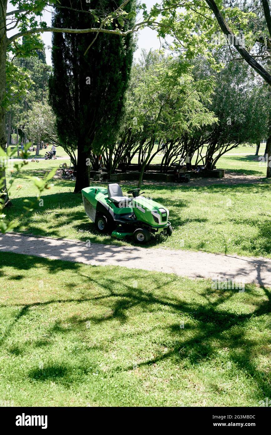 Der motorisierte große Rasenmäher steht in der Nähe der Bäume im Park Stockfoto