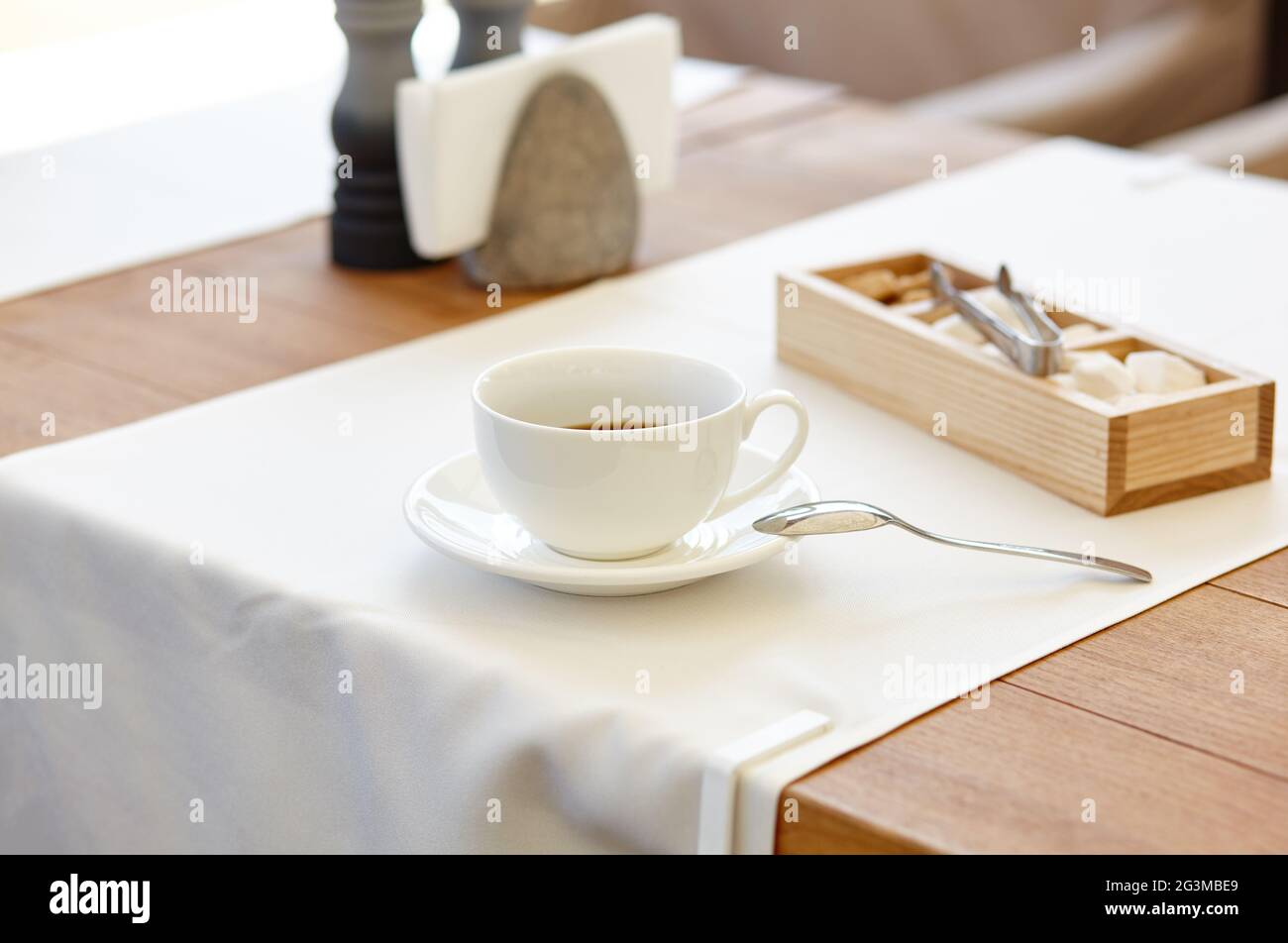 Heißer Kaffee in einer Tasse auf einem Holztisch. Modernes Design, Restaurant verwischen Hintergrund mit Bokeh-Bild Stockfoto