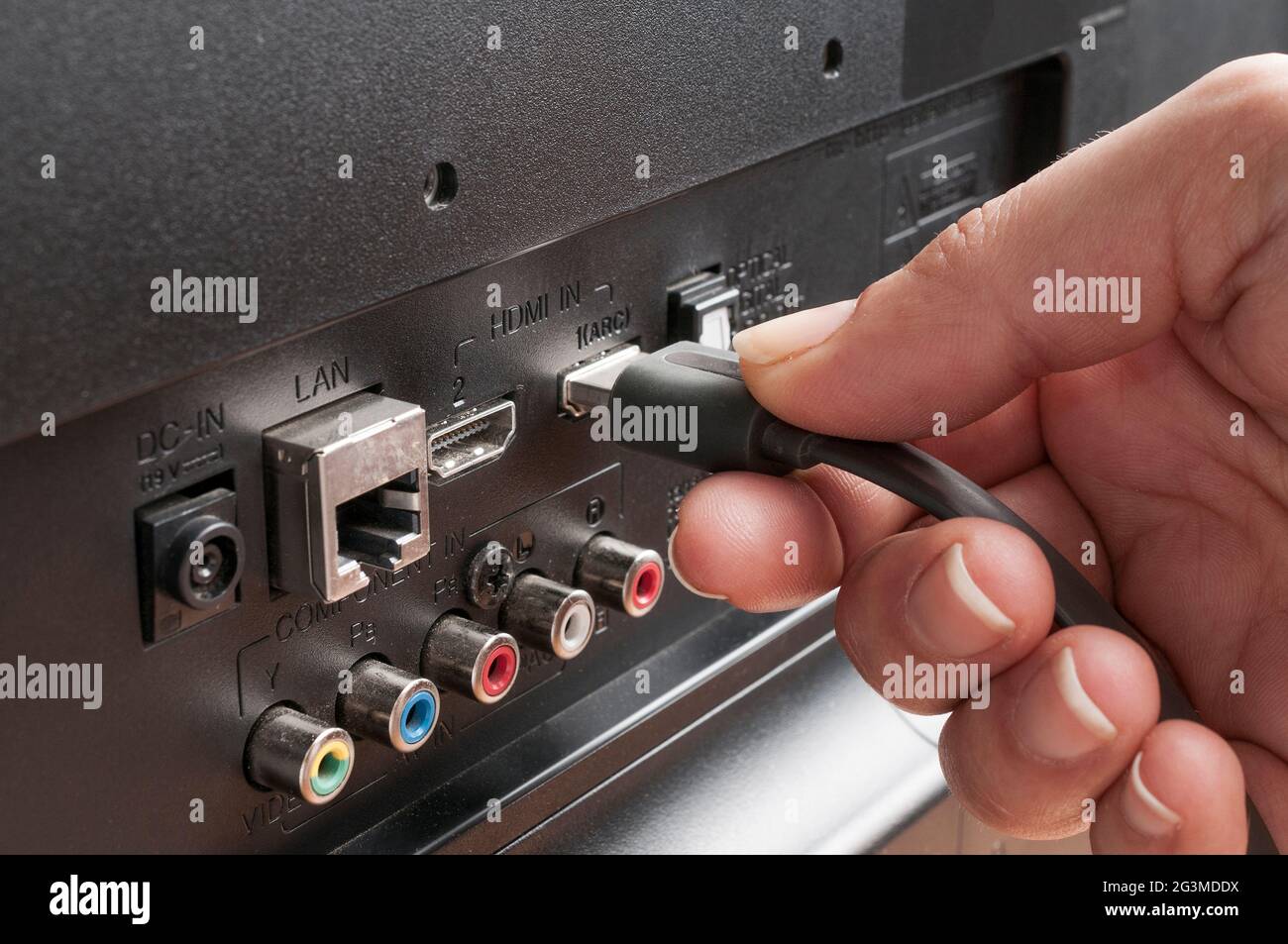 Frau steckt ein hdmi-Kabel an einen fernseher an Stockfoto