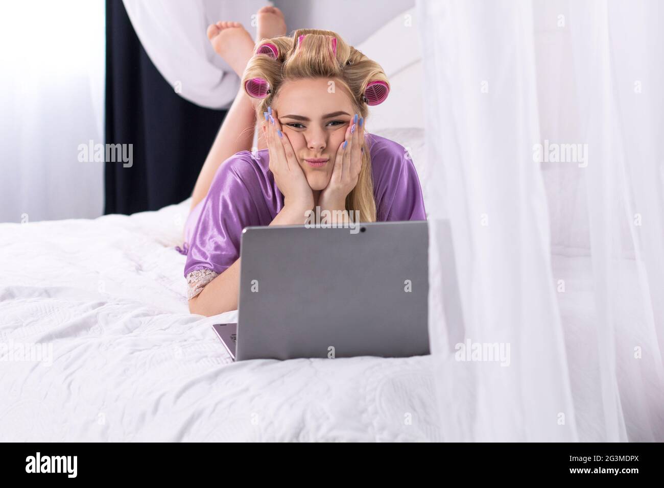 Junge Frau mit Laptop im Bett. Stockfoto