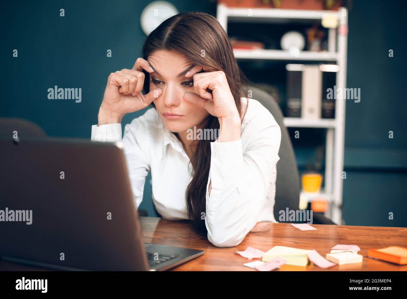 Frau, die versucht, ihre Augen offen zu halten, während Sie arbeiten. Stockfoto