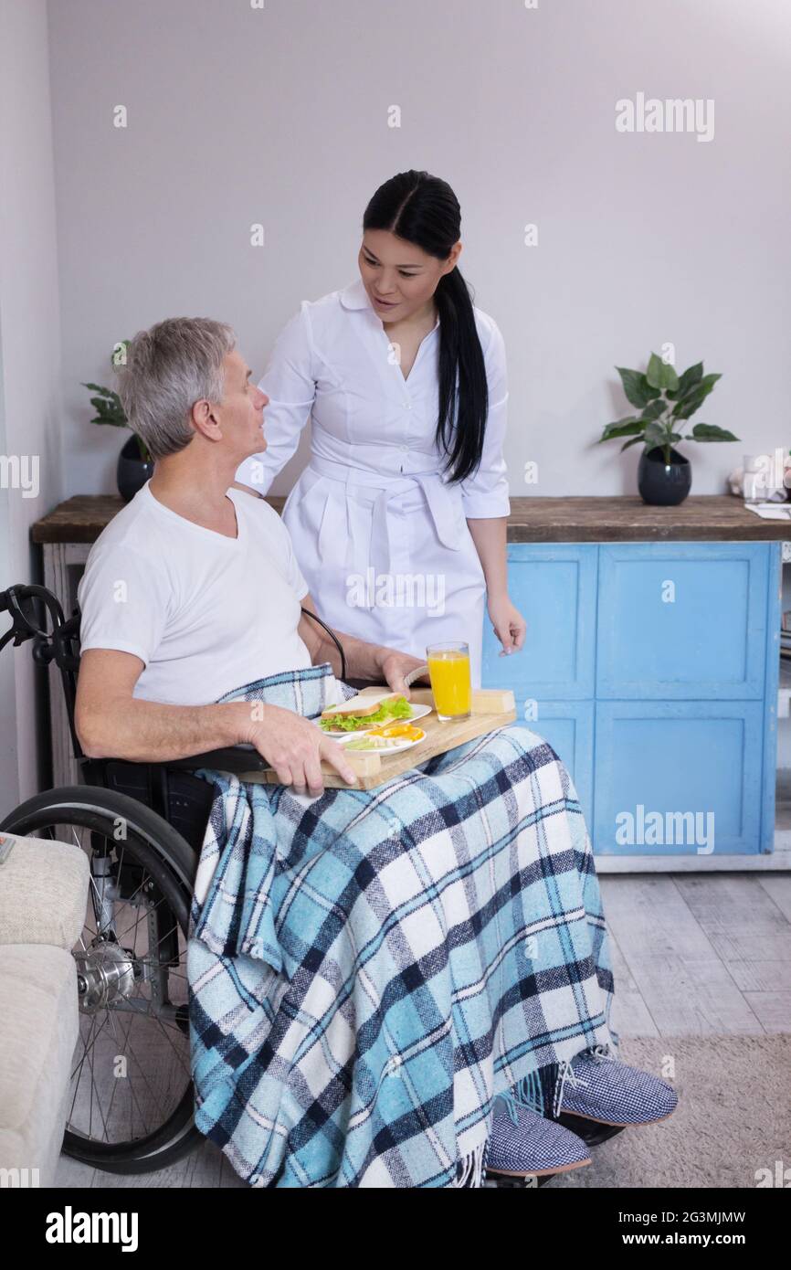 Krankenschwester, Nahrung zu Patienten im Rollstuhl. Stockfoto