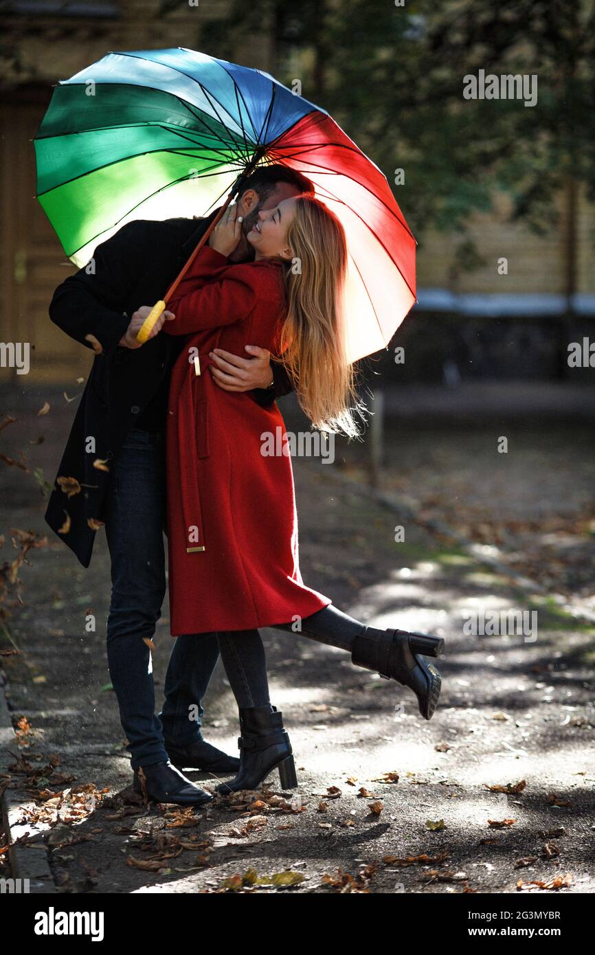 Junge Menschen wandern im Park unter bunten Regenschirm Stockfoto