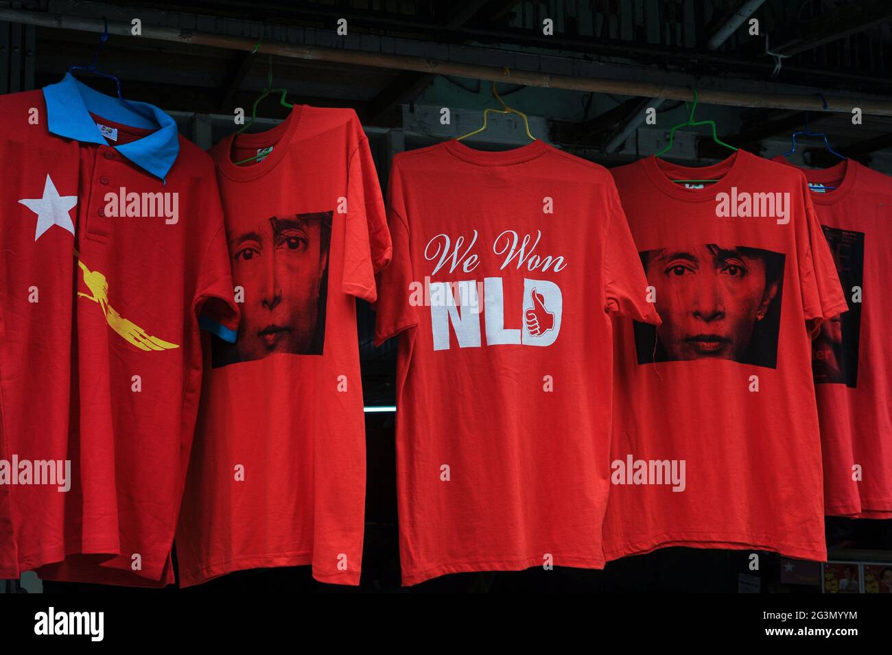 '10.11.2015, Yangon, , Myanmar - Rote T-Shirts mit dem Bild von Aung San Suu Kyi und der Aufschrift 'We won NLD' stehen in der Form an einem Straßenstand zum Verkauf Stockfoto